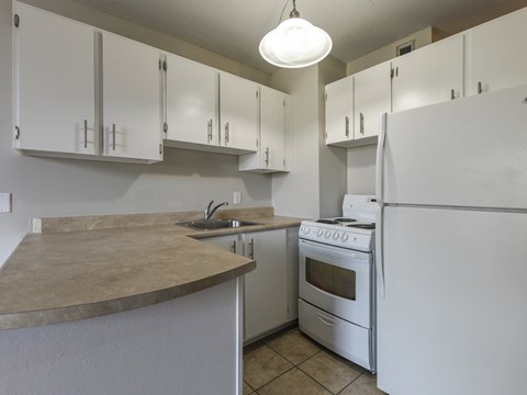A kitchen with white cabinets and a white refrigerator.
