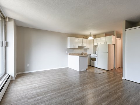 A kitchen with white cabinets and a wooden floor.