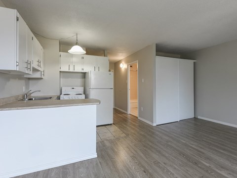 A kitchen with white cabinets and a wooden floor.