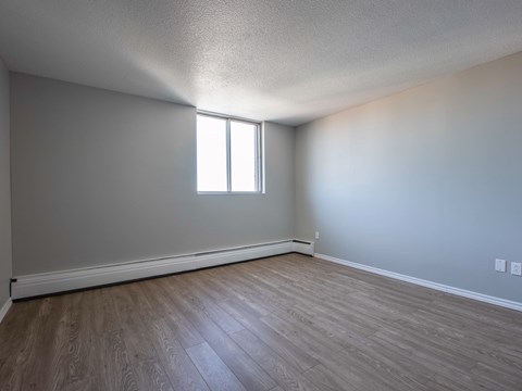 A room with a window and wooden flooring.