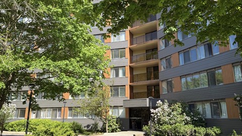 A modern apartment building with balconies and surrounded by greenery.