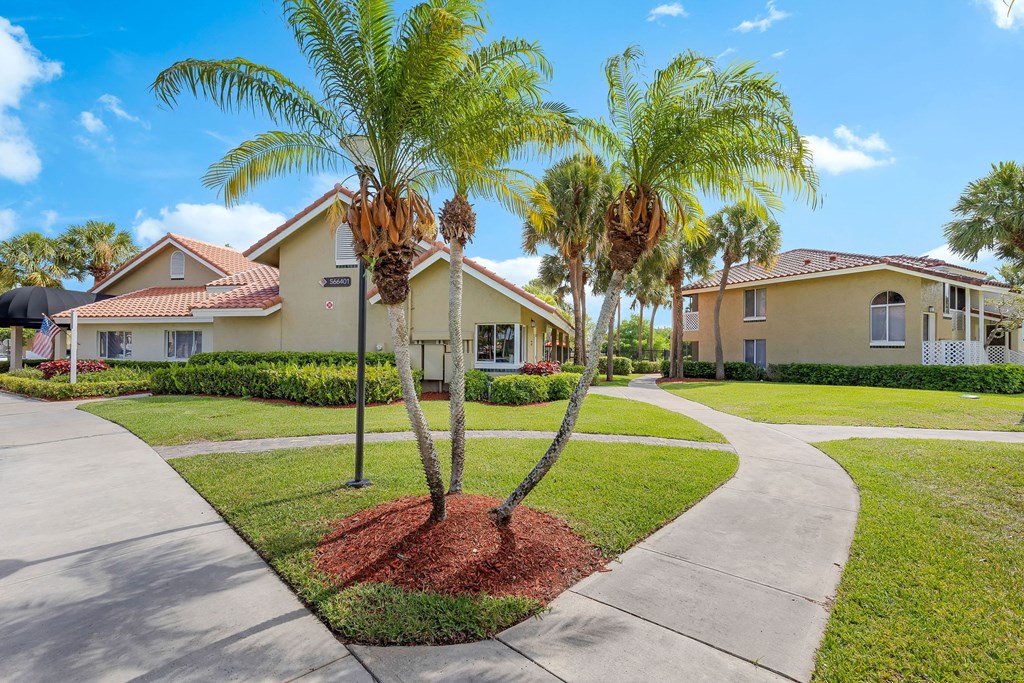 a sidewalk with palm trees in front of some houses
