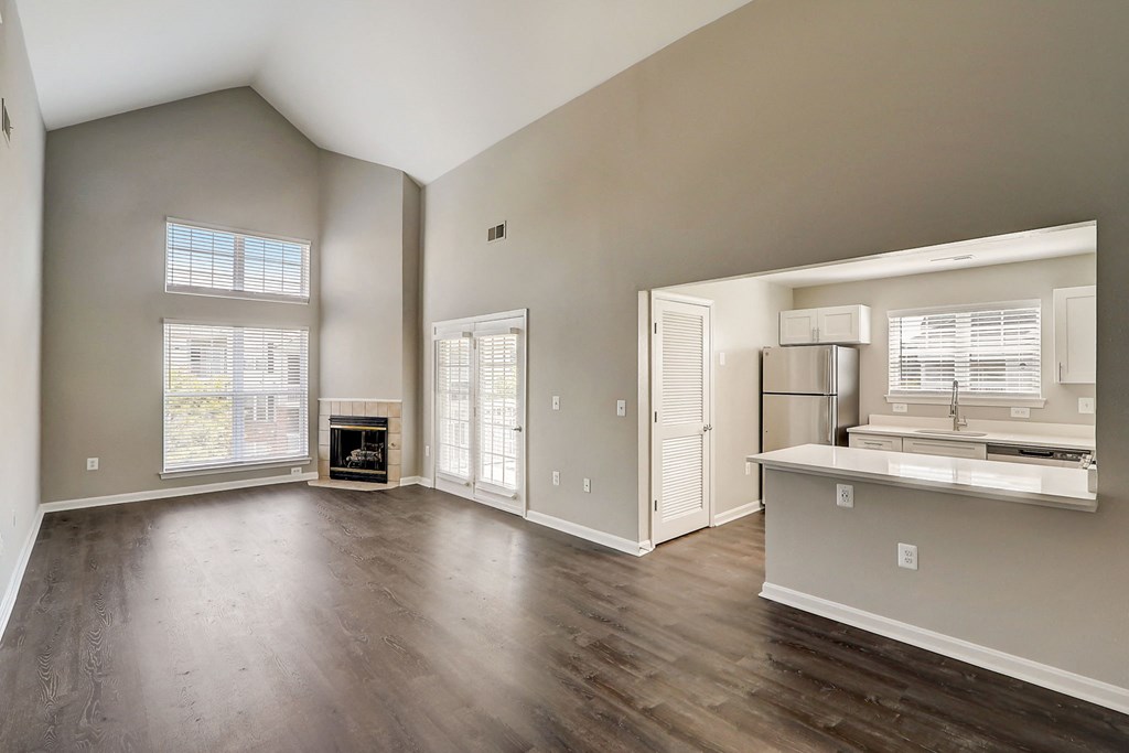 an empty living room with a fireplace and a kitchen