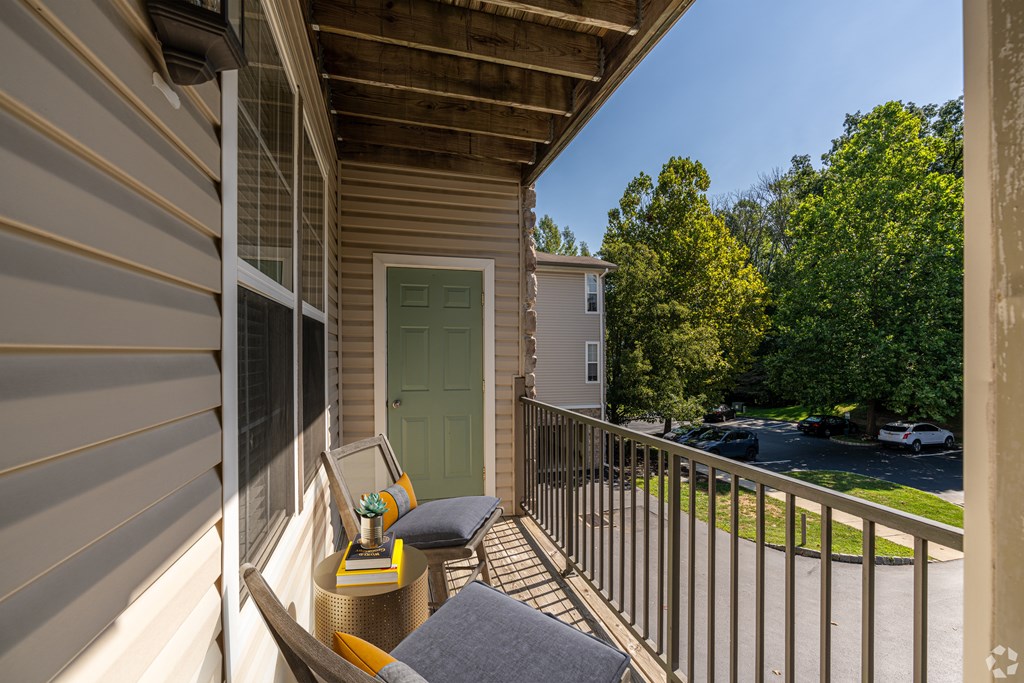 A balcony with a chair and a table with a vase of flowers on it.