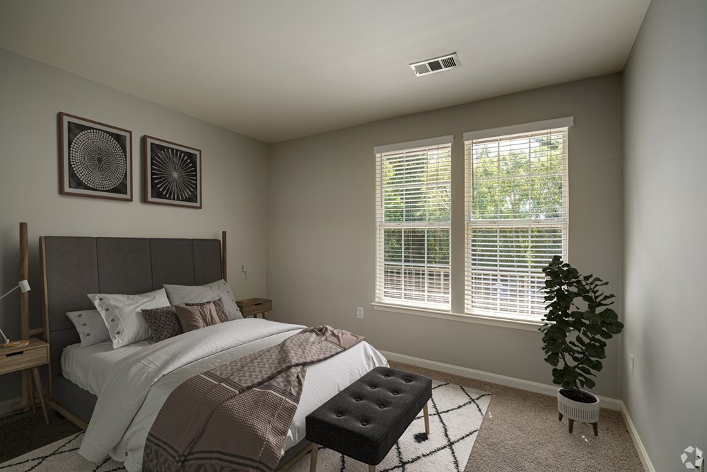 A bedroom with a bed, a bench, and two wall art pieces.