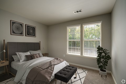 A bedroom with a bed, a bench, and two wall art pieces.