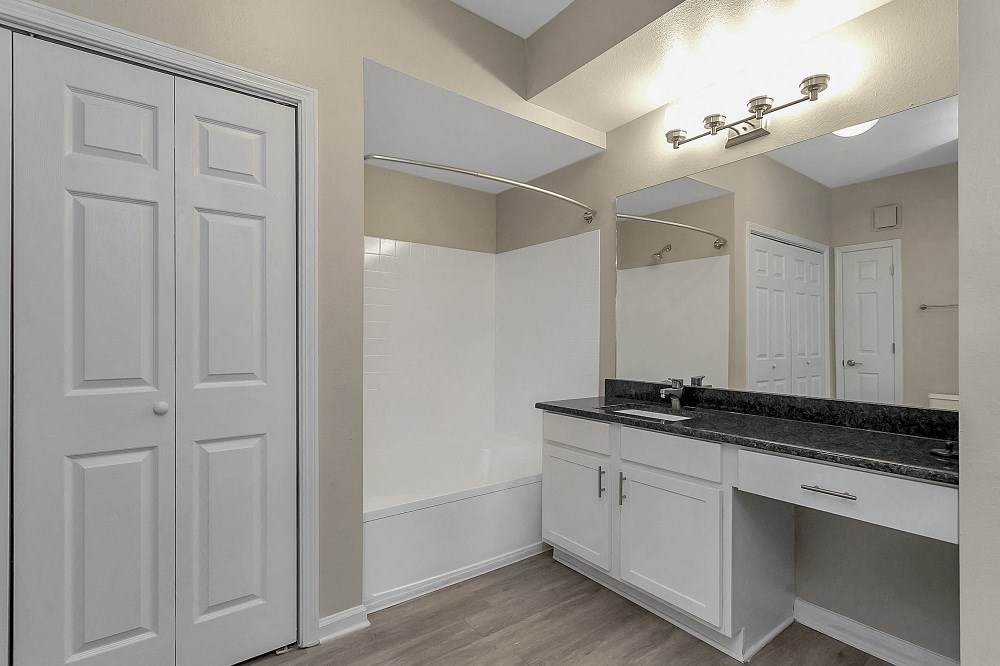 a bathroom with white cabinets and a sink and a mirror