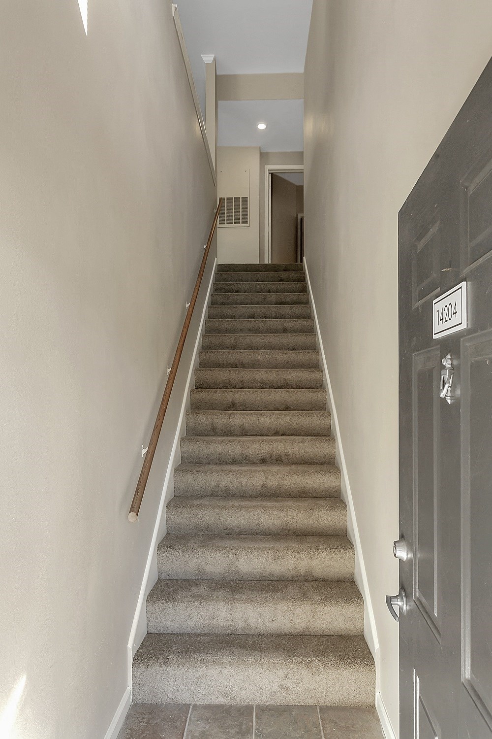 a stairway leading up to a hallway with a black door