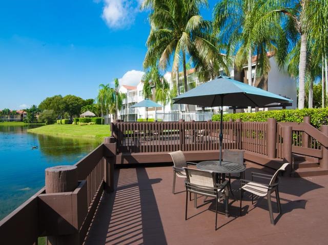 a patio with tables and chairs next to a body of water