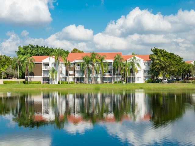 an apartment building overlooking a lake with palm trees