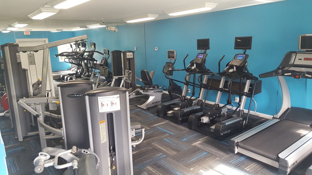 a gym with cardio equipment and weights on the floor