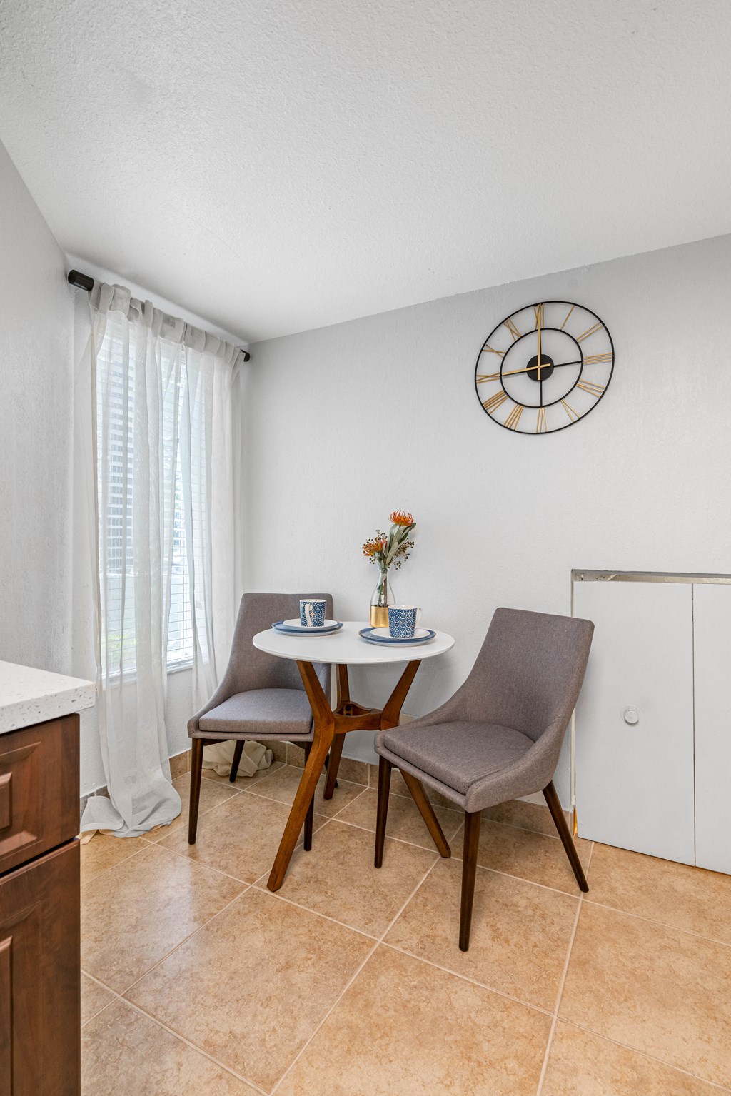 a dining area with two chairs and a table with a clock on the wall