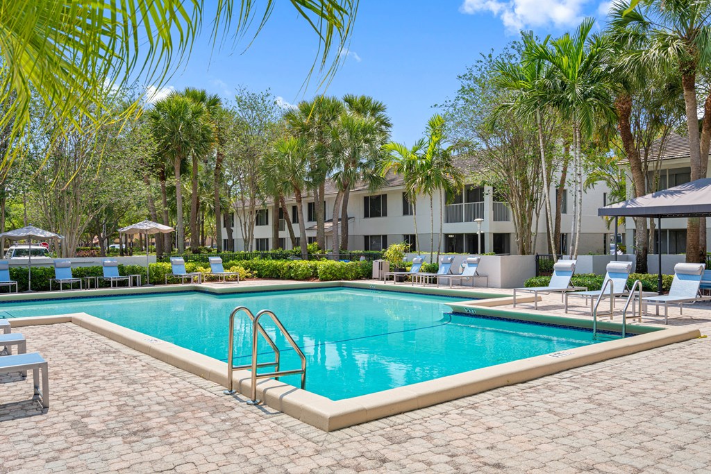 a swimming pool in front of a hotel with palm trees