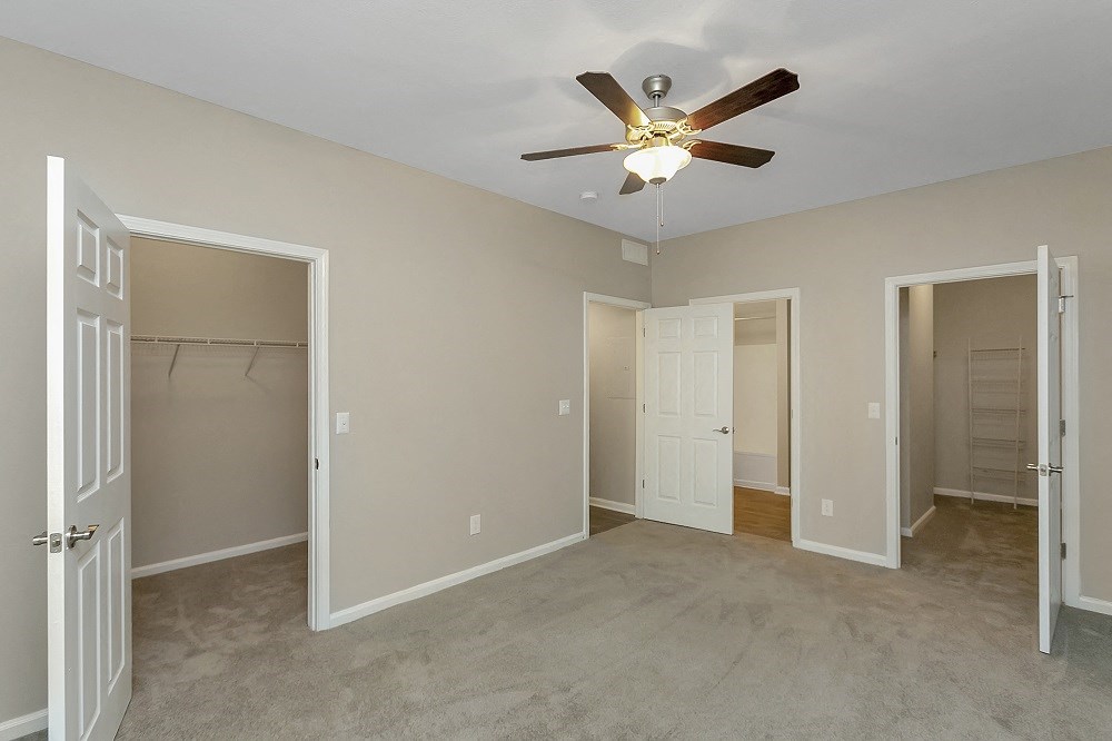 an empty bedroom with a ceiling fan and closet
