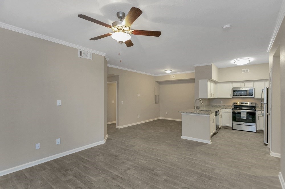 an empty kitchen and living room with a ceiling fan