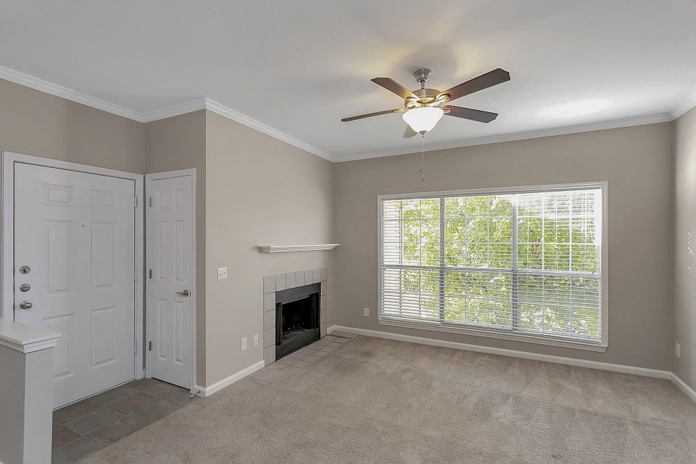 an empty living room with a fireplace and a ceiling fan
