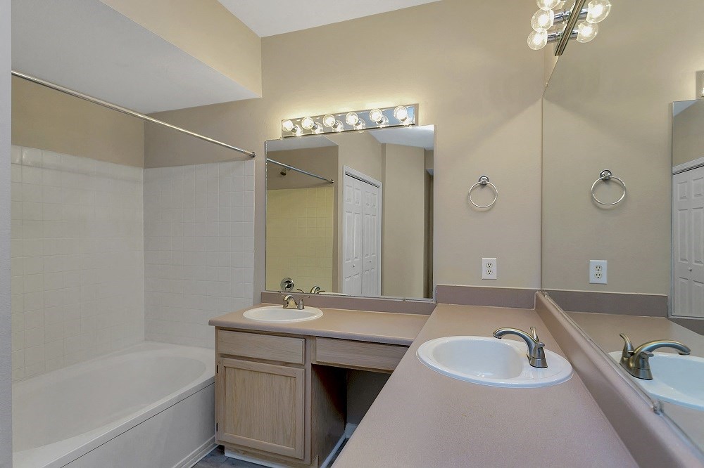 a bathroom with two sinks and a tub and a mirror
