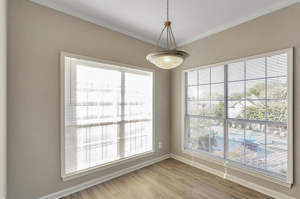 an empty living room with two large windows and a lamp