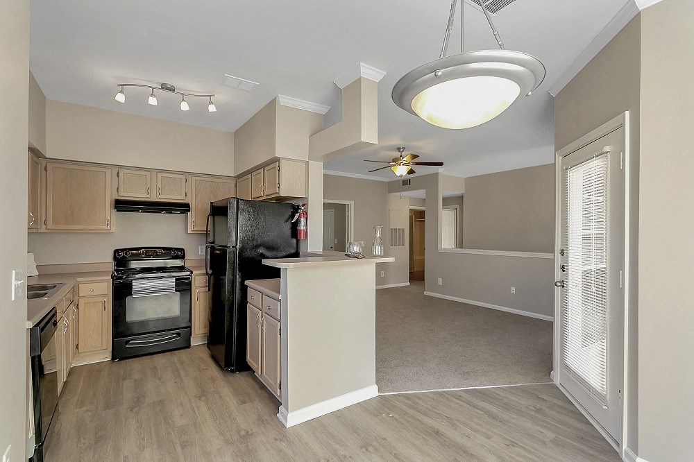 an open kitchen and living room with a black stove and refrigerator