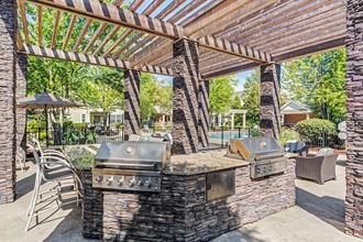 Apartments for Rent in Aurora - The Apartments at Kirkland Crossing - Outdoor Grilling Area with Outdoor Furniture And Wood Slat Roofing