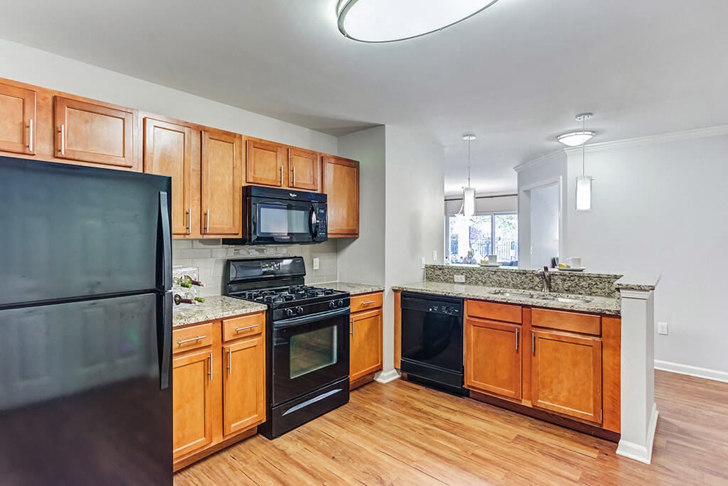 Aurora IL Townhomes - The Apartments at Kirkland Crossing - Spacious Kitchen with Wood Cabinets, Granite Countertops, and Black Appliances