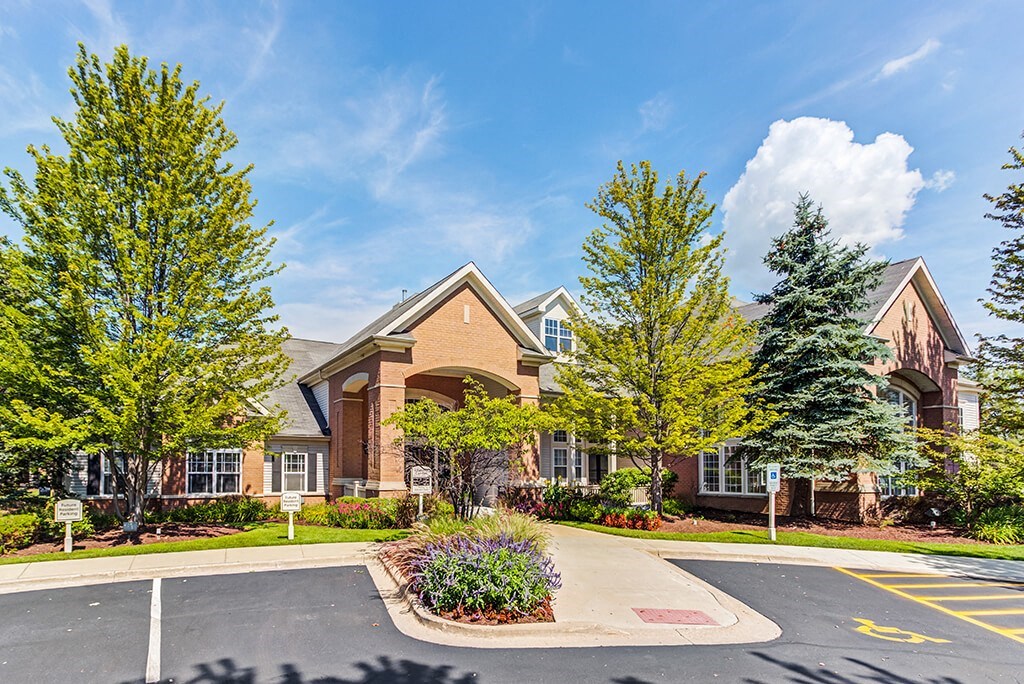 Aurora Apartments for Rent - The Apartments at Kirkland Crossing - Exterior Apartment Building with Tall Trees and Empty Parking Lot