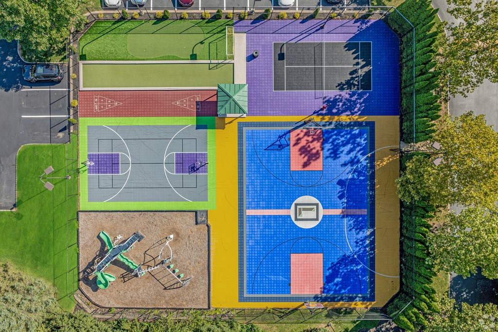 A colorful outdoor sports complex with a basketball court, a tennis court, and a volleyball court.