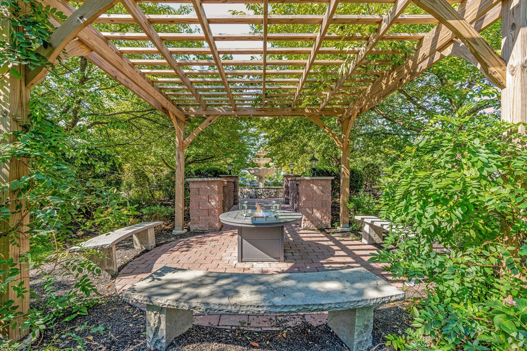 A wooden pergola with a table and chairs under it.