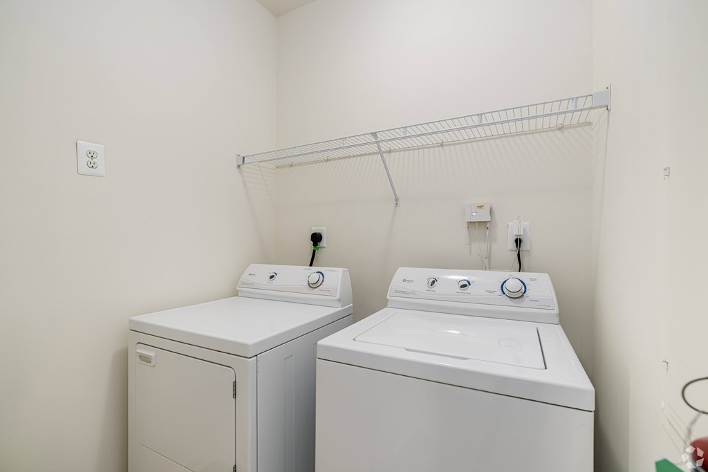 Two white front loading washing machines in a small laundry room.