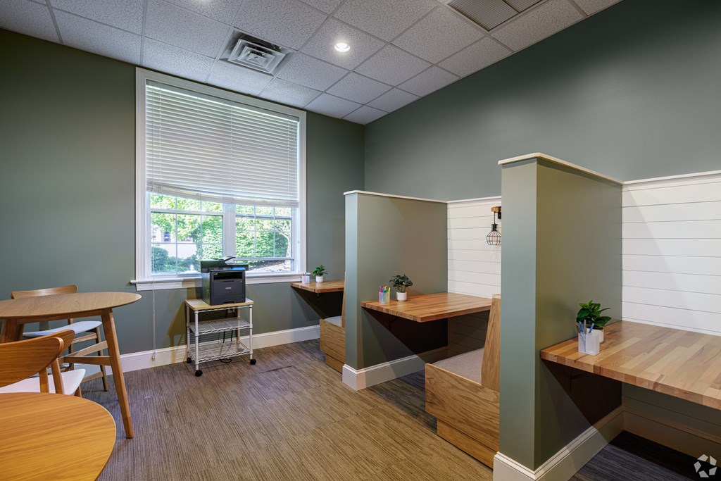 A room with a table, chairs, and a laptop on a cart.