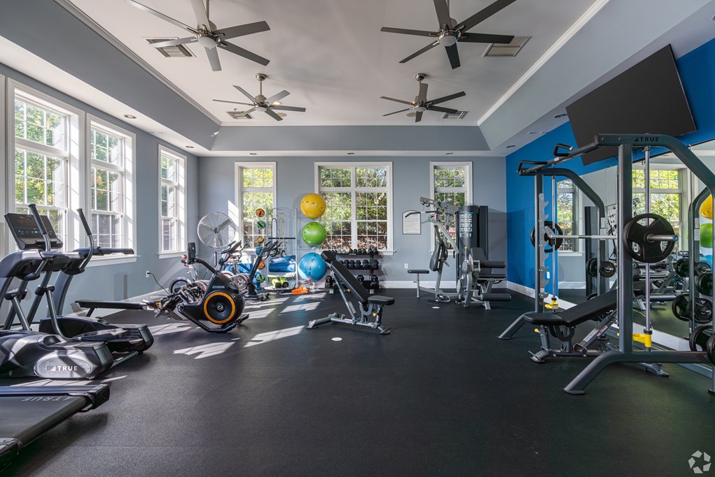 A gym with a variety of exercise equipment including treadmills, stationary bikes, and weight machines.