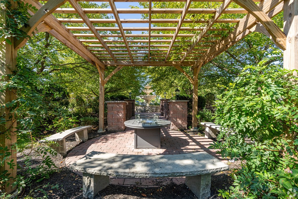 A wooden pergola with a table and chairs under it.