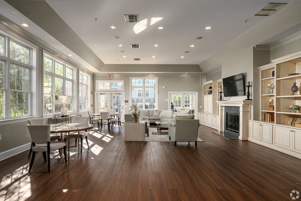 A large, well-lit living room with wooden floors and furniture.