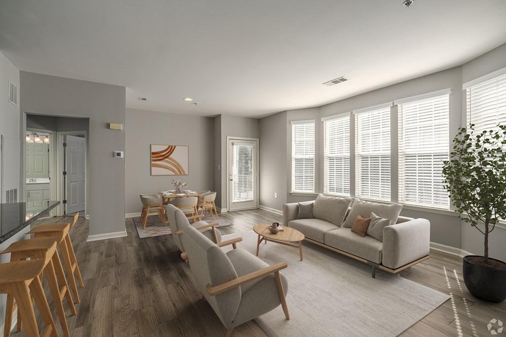 A modern living room with a grey sofa, wooden chairs, and a coffee table.