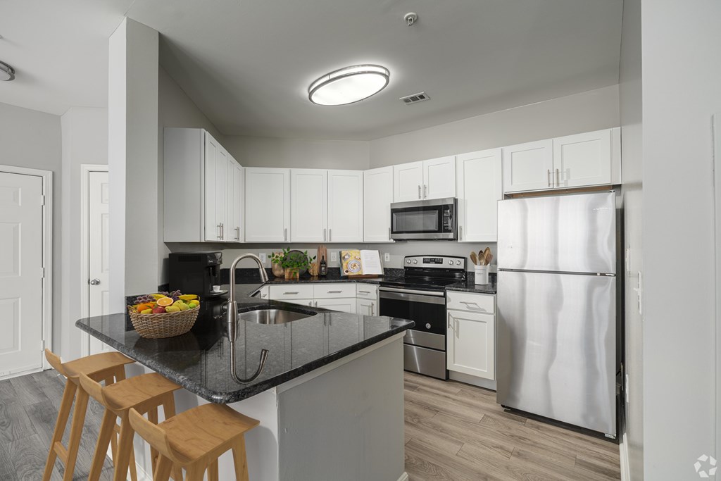 A kitchen with white cabinets and a black countertop.
