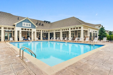 Luxury Apartments In Vernon Hills, IL - The Oaks of Vernon Hills - Resort-Style Swimming Pool With Lounge Chairs, And Resident Clubhouse In The Background