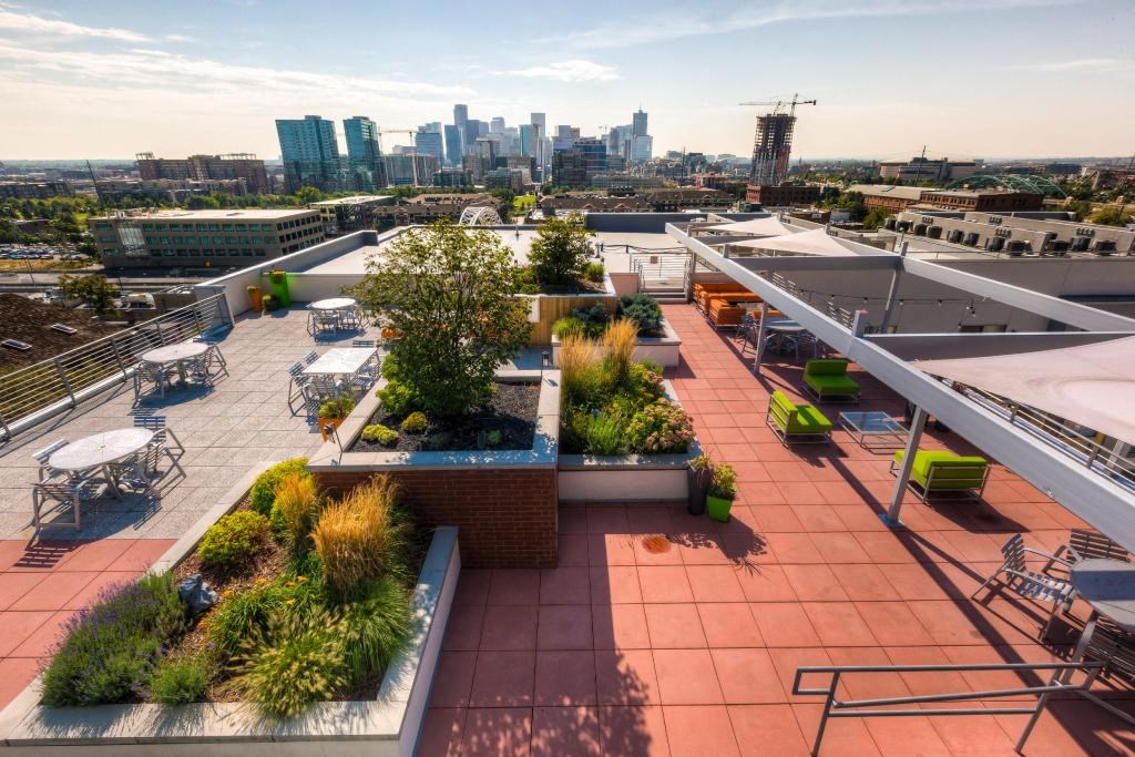 Studios in Denver CO - Line 28 LoHi - Modern Kitchen with Stainless Steel Oven, Stove, Refrigerator, and Microwave, with Wood-Style Cabinetry, Granite Counters, and Tile Backsplash
