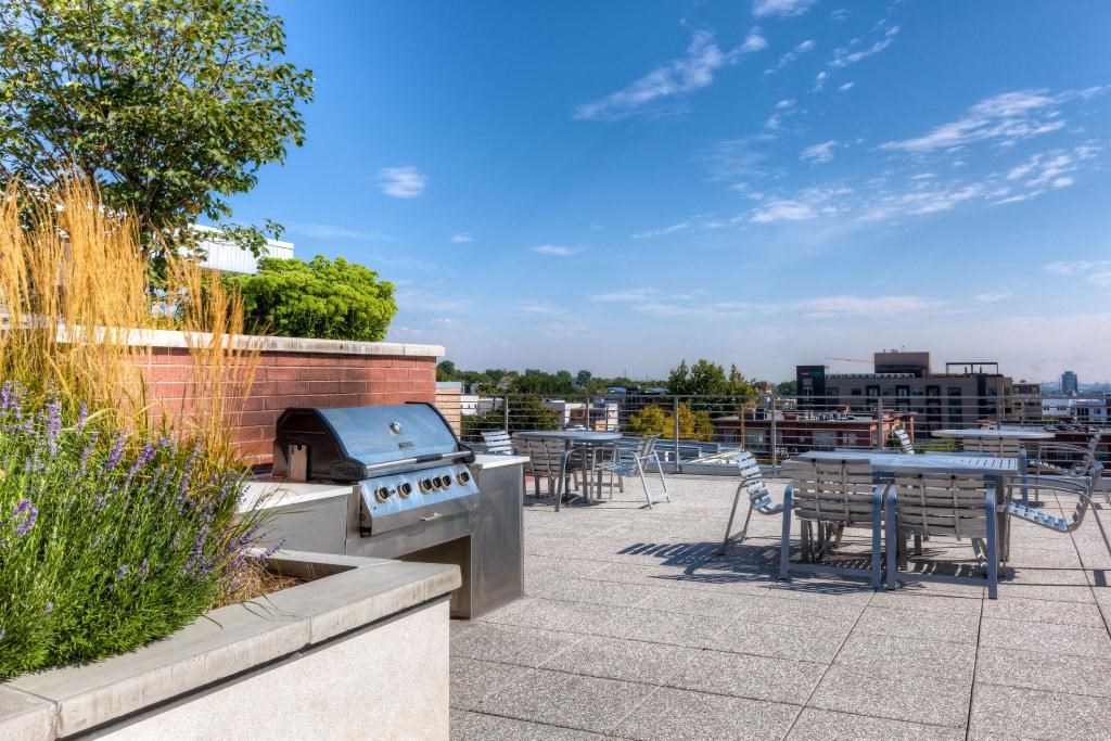a barbecue grill on the roof of a building with tables and chairs