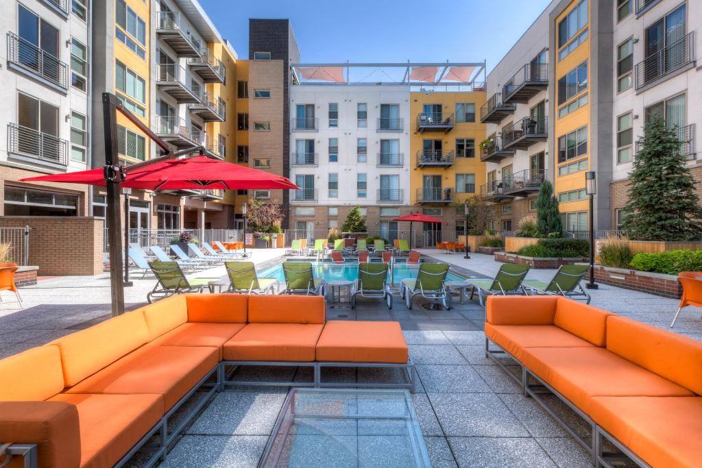 an outdoor lounge area with tables and chairs in an apartment building