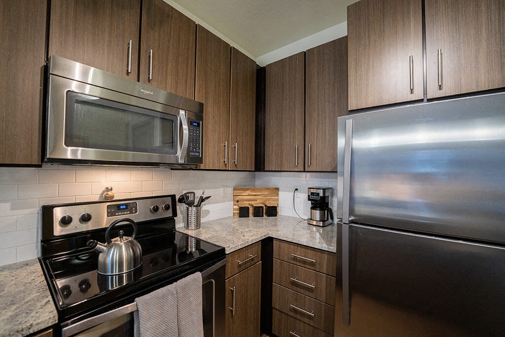 Apartments for Rent in Denver CO - Line 28 LoHi - Rooftop Lounge with City Views, Plant Boxes, Red Tile, Tables and Chairs, and Umbrellas