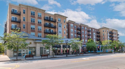A street view of a multi-story apartment building with a storefront at the ground level.