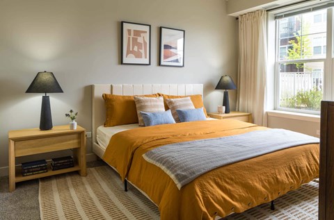 A bedroom with a bed, nightstand, and two lamps.