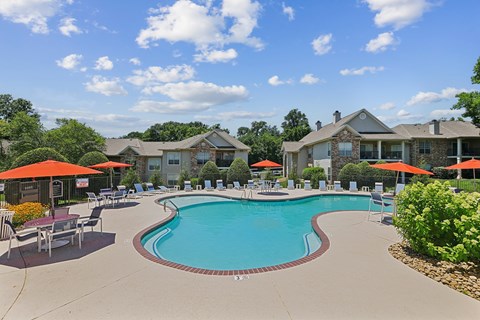 A swimming pool surrounded by lounge chairs and umbrellas in a residential area.
