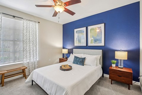 A bedroom with a bed, nightstands, and a ceiling fan.