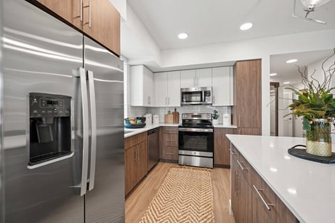 A modern kitchen with a stainless steel refrigerator and wooden cabinets.