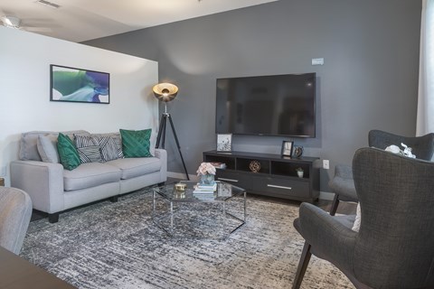 A living room with a grey couch, a coffee table, a television, and a chair.