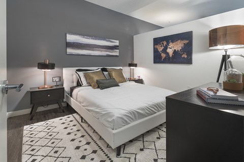 A bedroom with a large bed, a nightstand, and a world map on the wall.