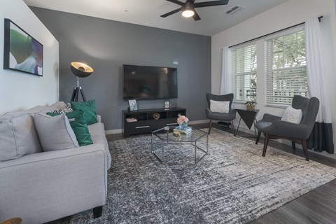 A living room with a grey couch, a black coffee table, and a flat screen TV.