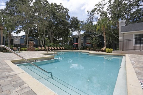 A small pool surrounded by a glass fence and trees.