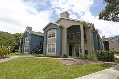 A blue and beige two-story apartment building with a staircase leading to the second floor.